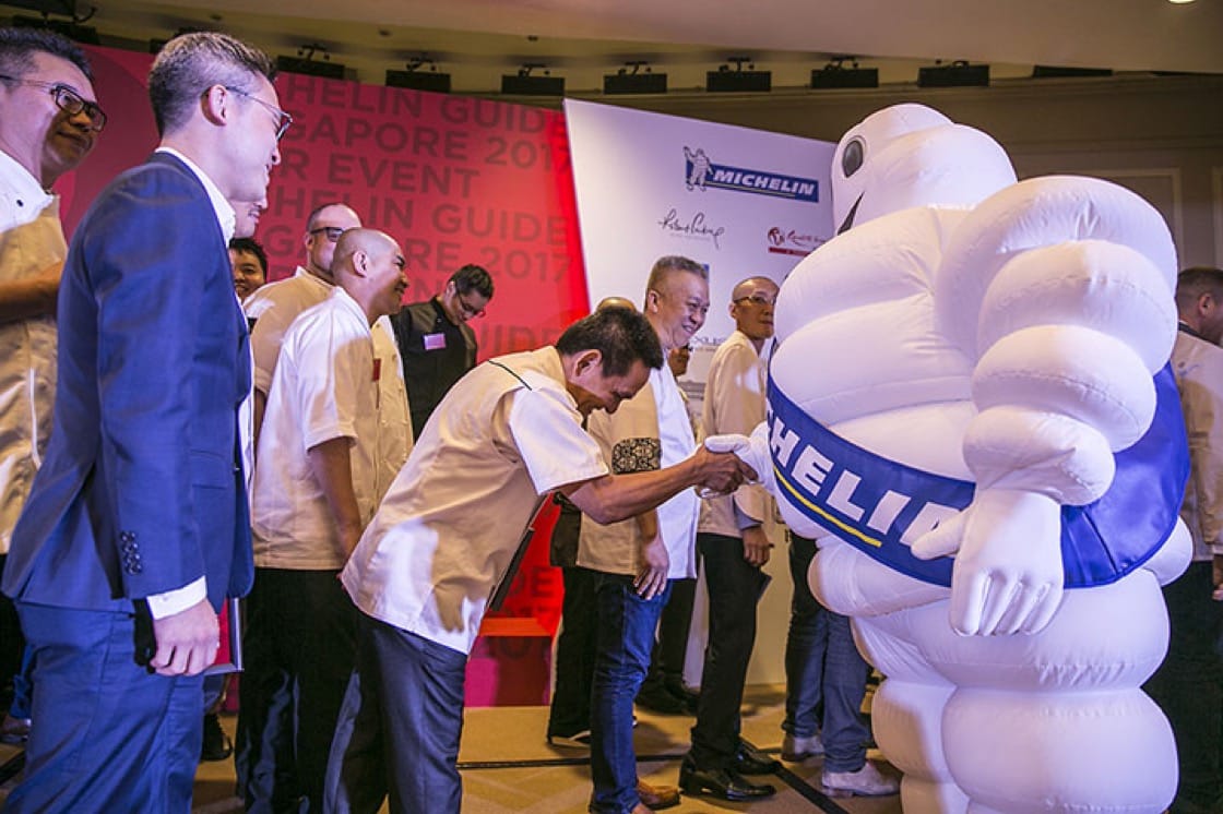 Hawker Chan who retains his Michelin star for Liao Fan Hong Kong Soya Sauce Chicken Rice & Noodle shakes hands with Bibendum, Michelin's mascot.