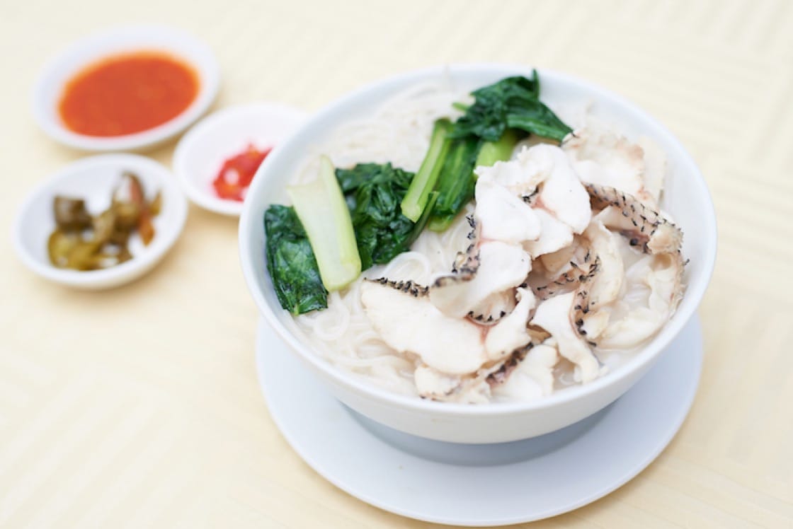 Rich, tasty sliced fish soup from Ka Soh served with cut bird's eye chilis and cubes of fried lard