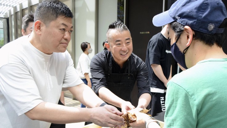Chefs Yoshiro Narisawa (right) of Restaurant Narisawa and Hisato Hamada of Wagyumafia distributing onigiri as part of their #Onigiriforlove project. Photo credit: Japan Times