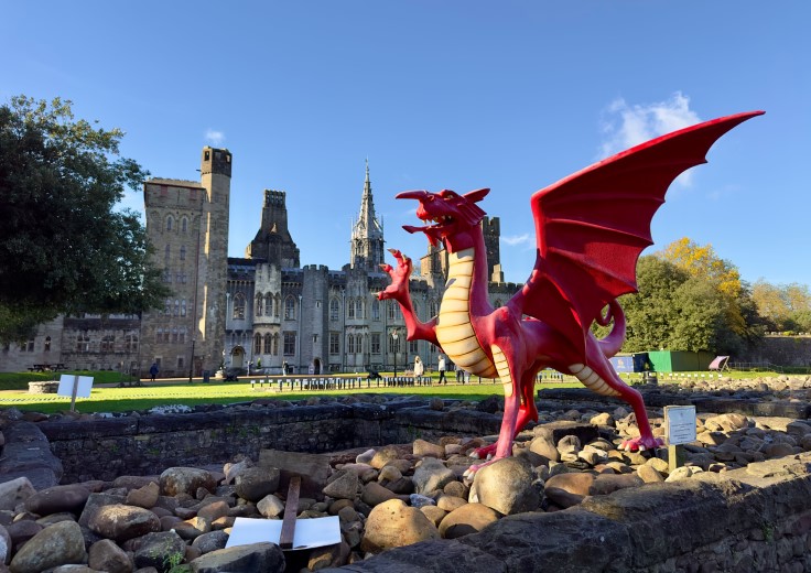 A statue of the iconic Welsh dragon in front of Cardiff Castle. © Wirestock/iStock